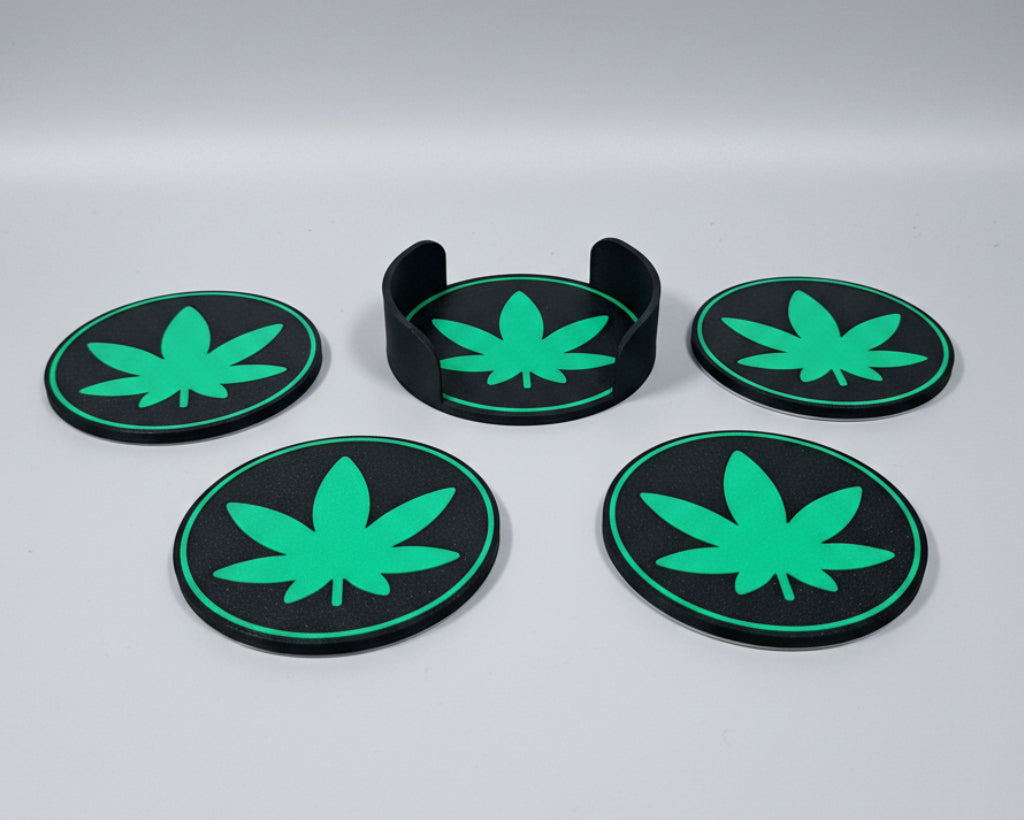 Five green cannabis leaf coasters on a grey surface
