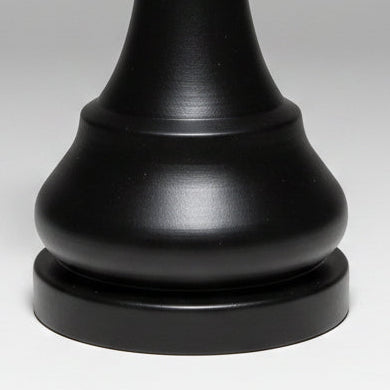 A matte black chess king piece centered on a light gray gradient studio background.