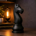 Black knight chess piece on a wooden shelf with decorative items and a world map in the background.