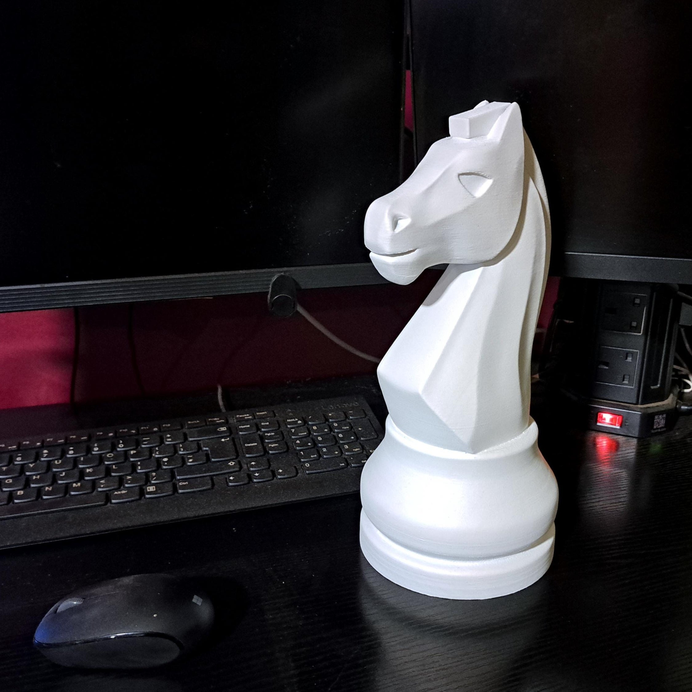 White chess piece on a desk with computer monitors in the background