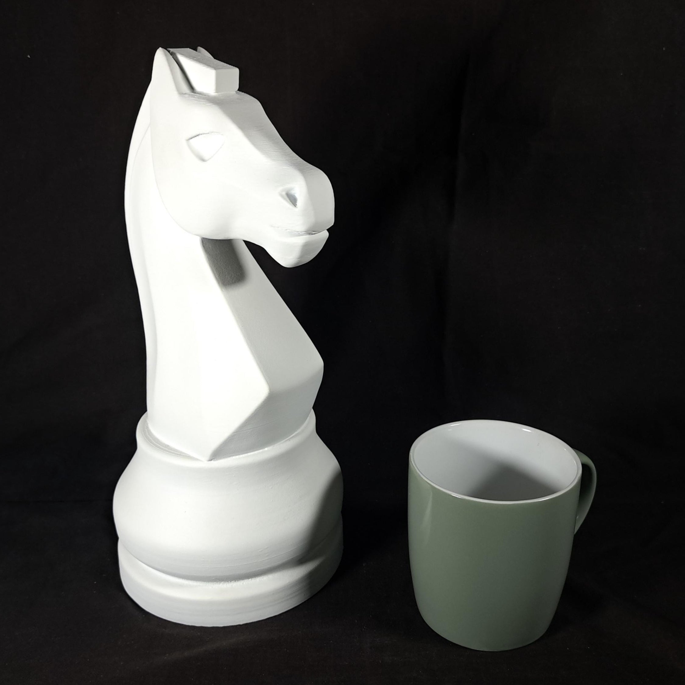 White knight chess piece next to a green mug on a black background