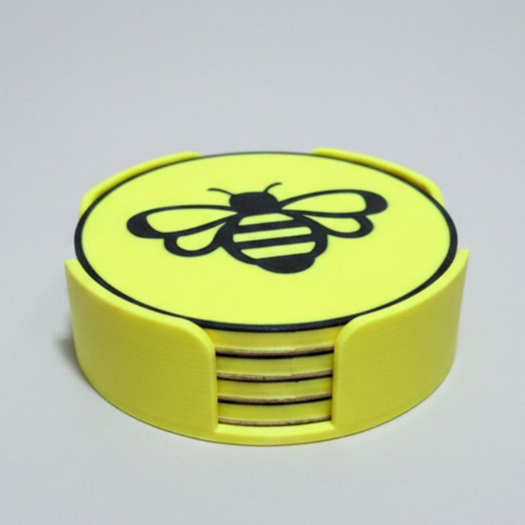 Close up shot of a set of yellow and black bee coasters in a holder on a grey background. 