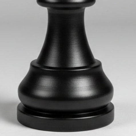 A close-up of a black chess piece, likely a bishop, with a matte and satin finish on a light gray background.
