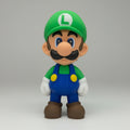 Toy figure of luigi in a green hat and blue overalls on a grey background