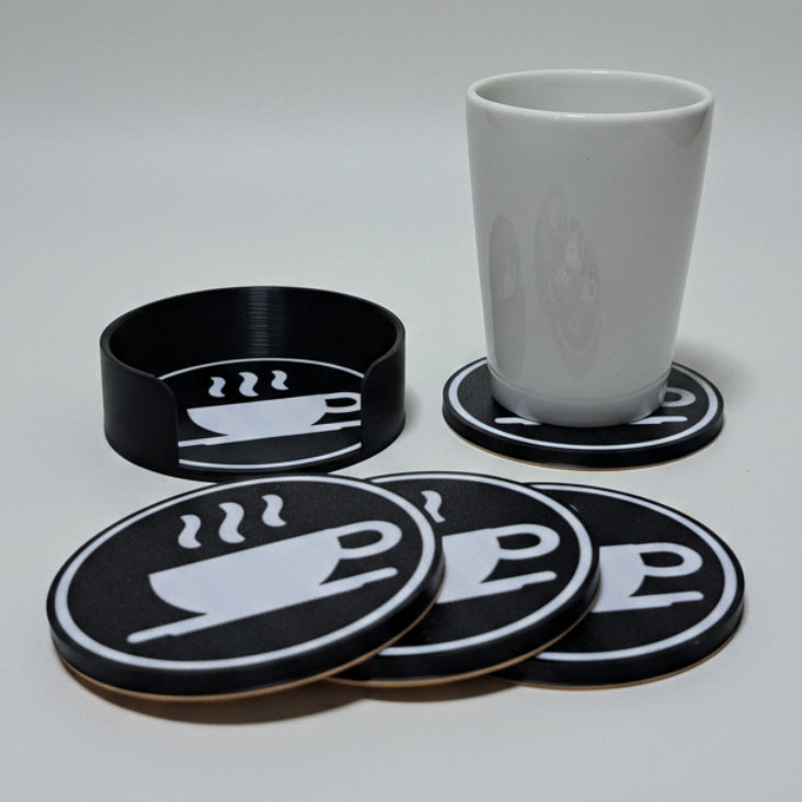 Set of black coasters with coffee cup design on a grey background.