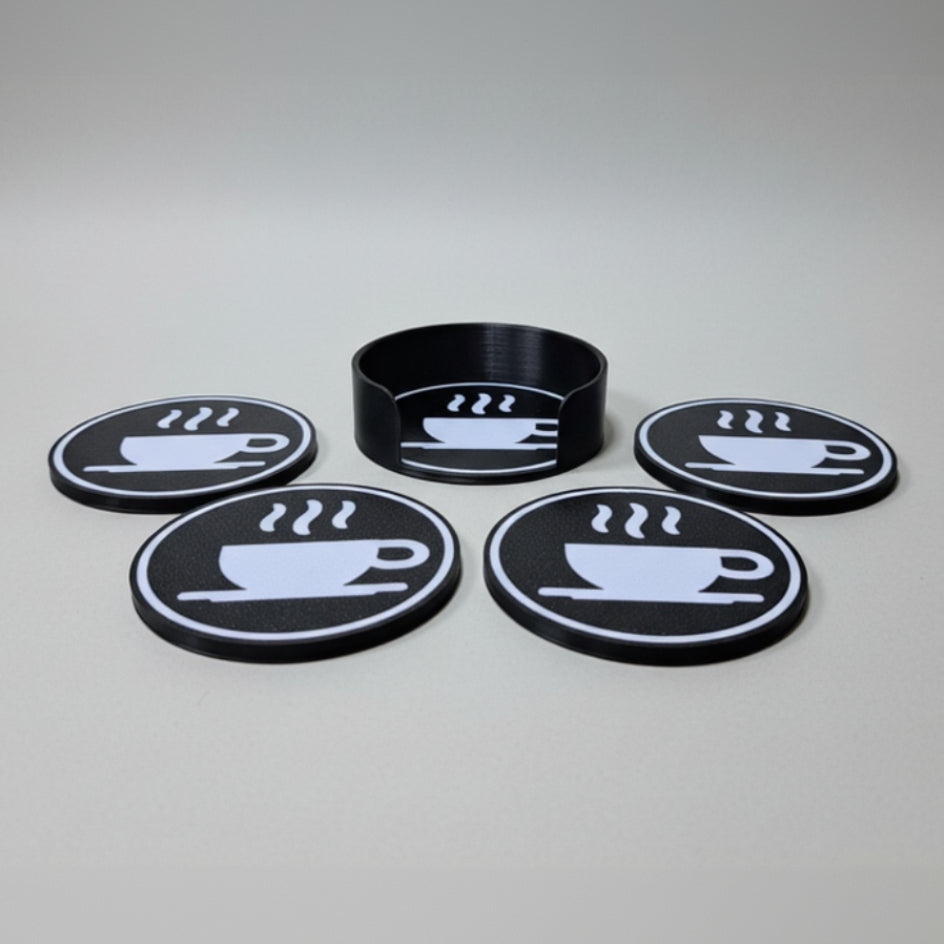 Set of black coasters with white coffee cup design on a grey background.