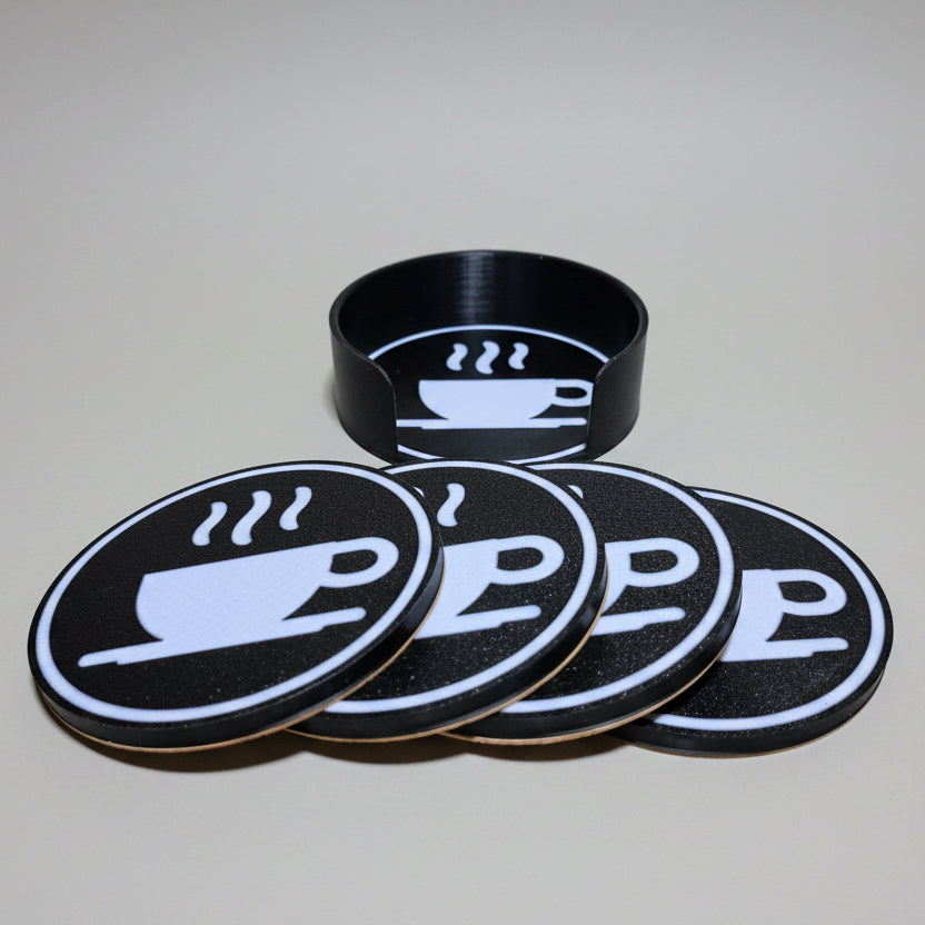 Set of black coasters with a white cup design on a grey background.