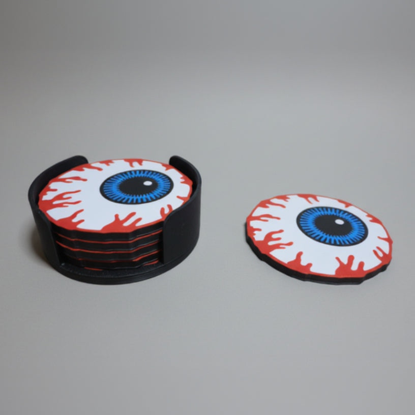 Eyeball-themed coasters with a matching holder on a grey background.