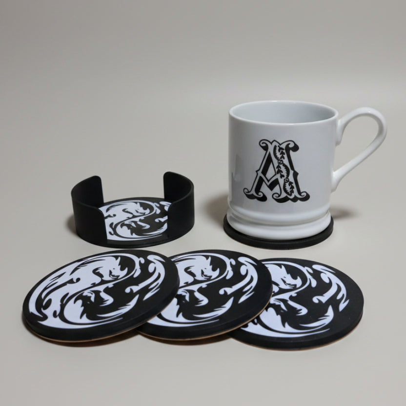 Set of black and white dragon coasters with a mug on grey background.