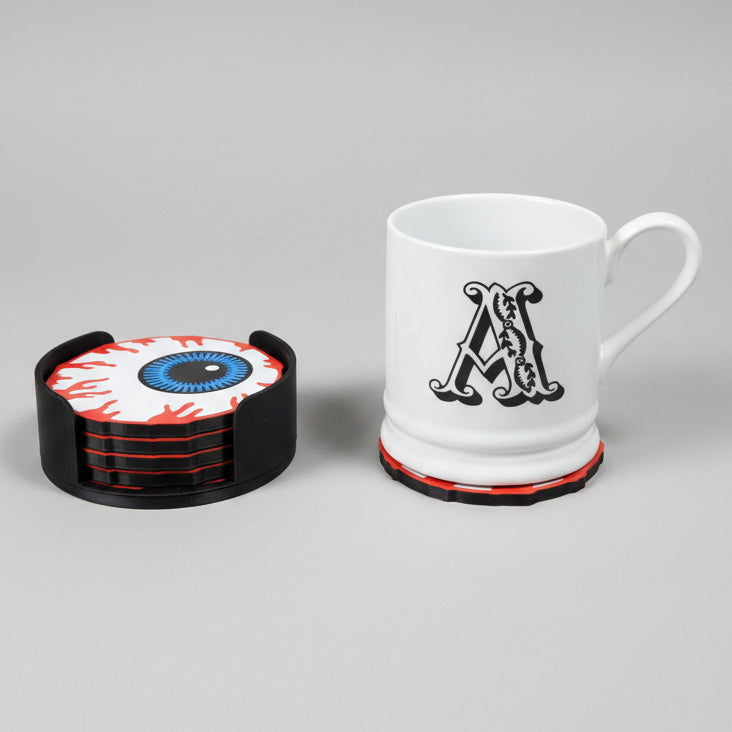 White mug on a eyball coaster with the other coasters in the matching holder on a grey background.