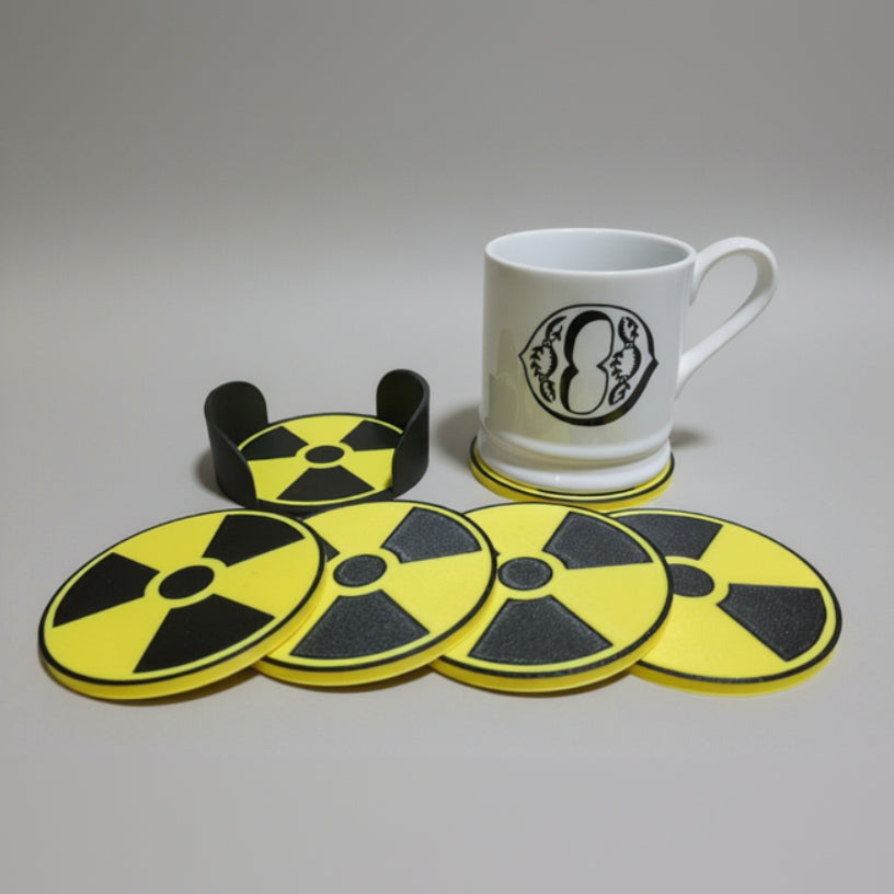 Nuclear symbol coaster set with a whit mug on a grey background.
