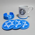 Blue coasters with star design on a grey surface, white mug with black logo.