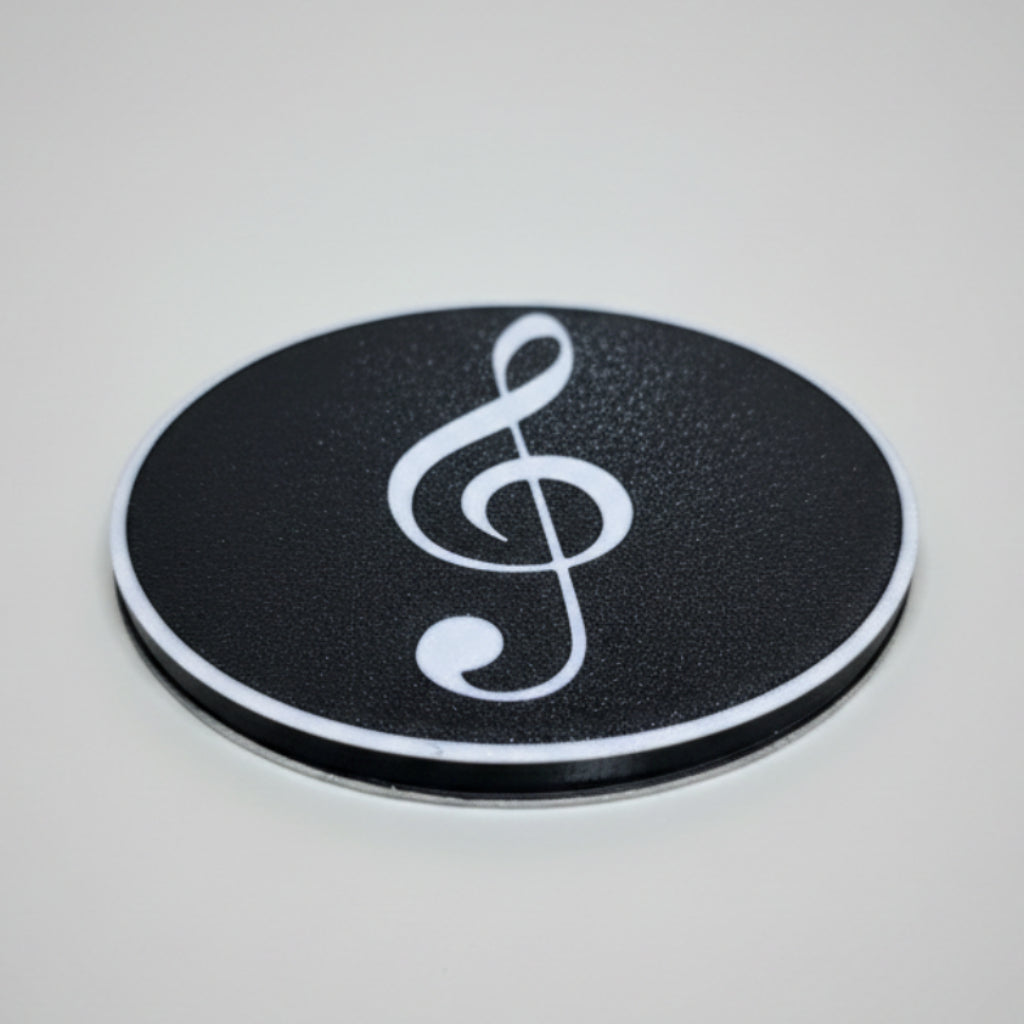 Black coaster with a white music symbol on a grey surface