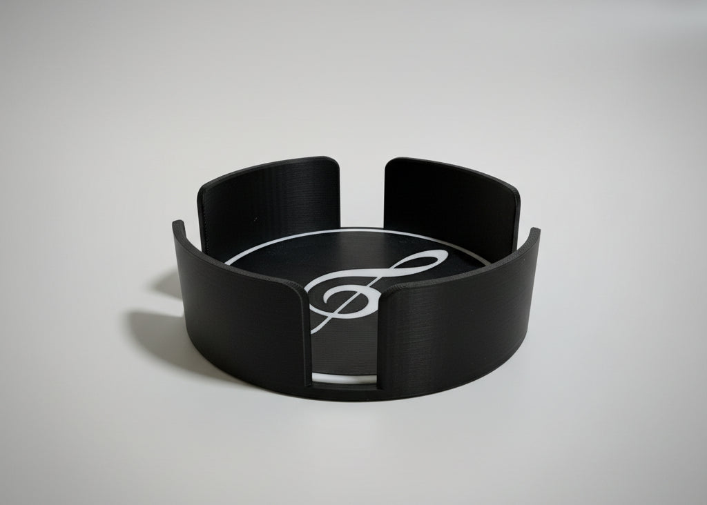 Black coaster holder with a treble clef design on a grey surface.