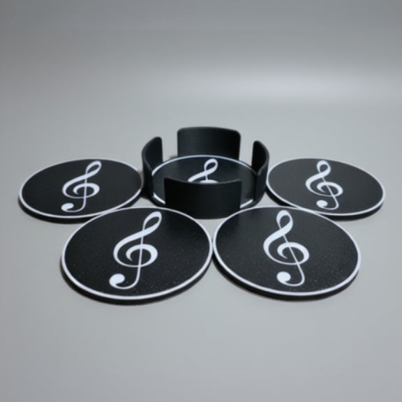 Black coasters with white treble clef symbols on a grey surface.