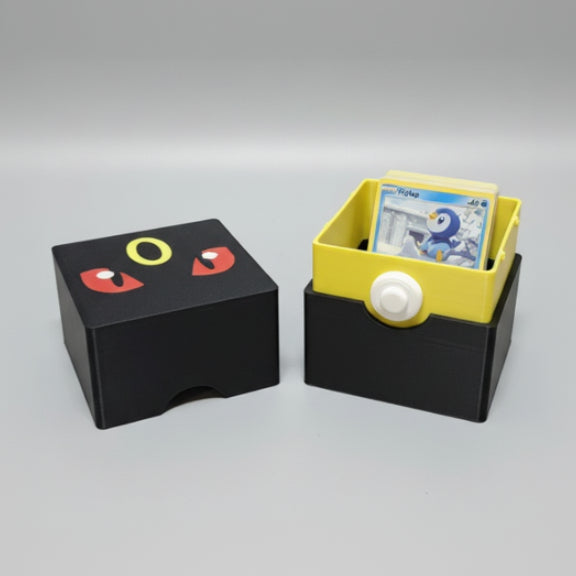 3D printed Umbreon Pokémon deck box open, showing yellow interior tray loaded with Pokémon cards, matte black exterior with Umbreon face lid detail.


