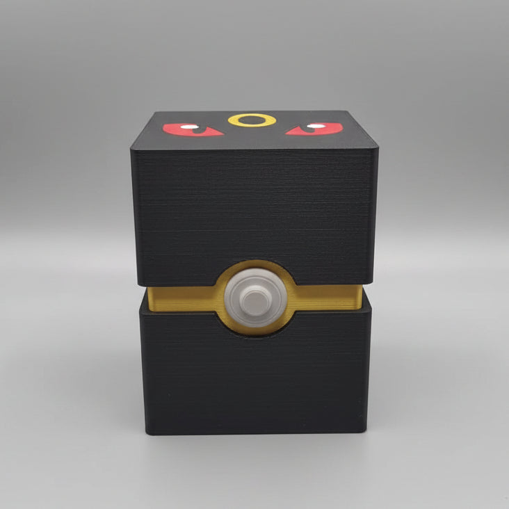 Front view of 3D printed Umbreon Pokémon deck box in matte black with gold Poké Ball clasp and Umbreon face lid art, showing layer texture finish.