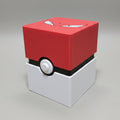 3D printed Poké Ball-style trading card deck box closed, red angry-eyes lid on white base with button detail, lifestyle shot on wooden table.