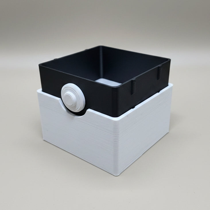 3D printed Poké Ball-style trading card deck box open, black inner tray with white base and button detail, studio shot.