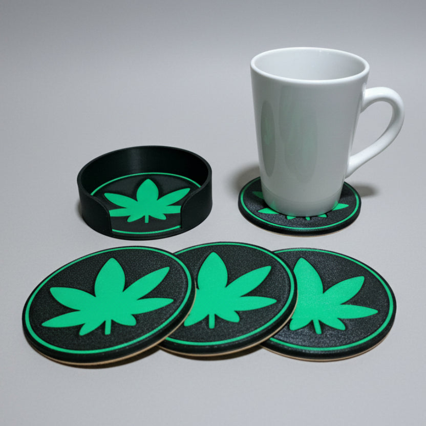 Set of four green leaf coasters on a grey background with a white mug.