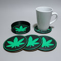 Set of four green leaf coasters on a grey background with a white mug.