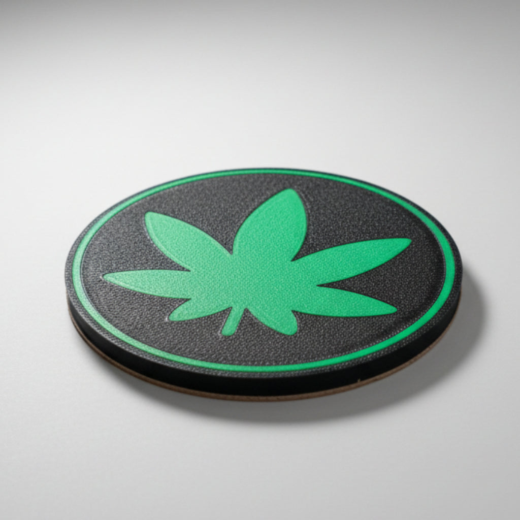 Green cannabis leaf coaster on a grey background.