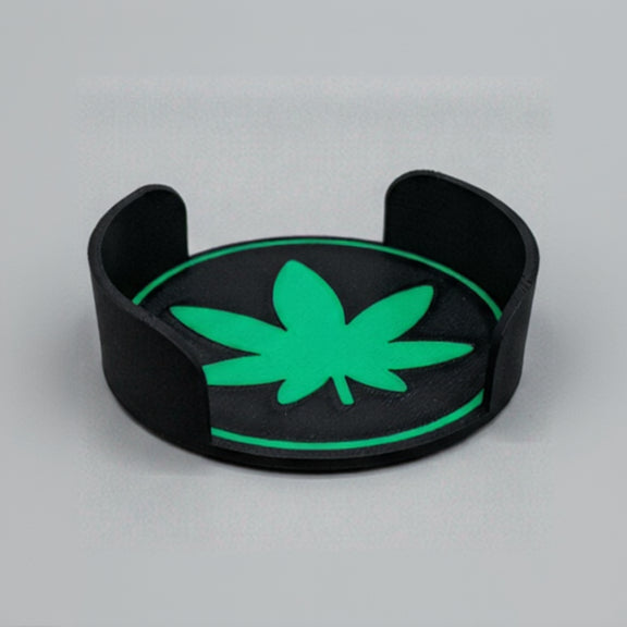 Black and green cannabis leaf-shaped object on a grey background.