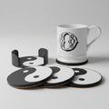 Set of black and white coasters with a mug featuring a yin yang symbol on a grey surface.