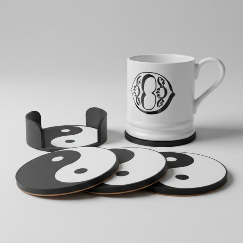 Set of black and white coasters with a mug featuring a yin yang symbol on a grey surface.