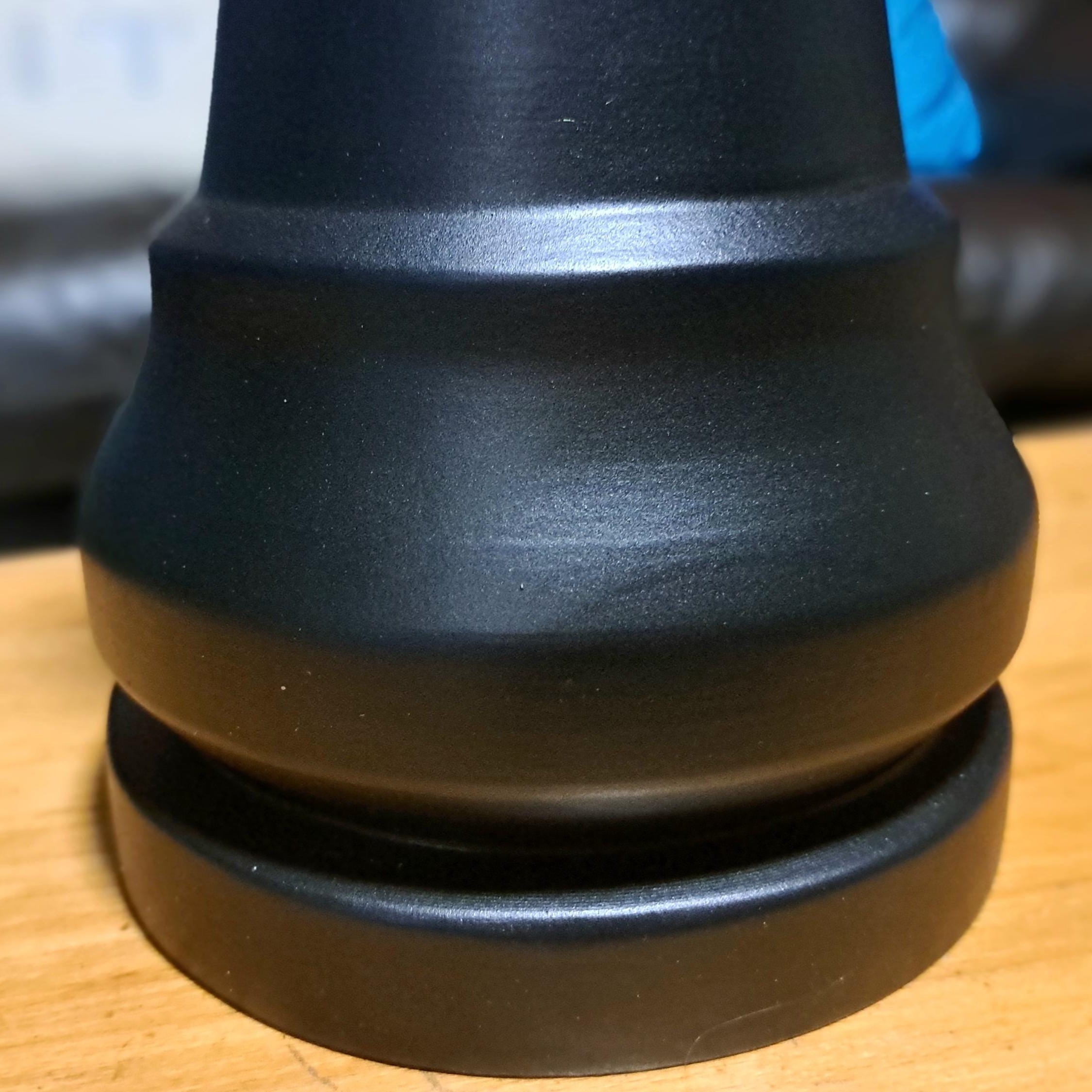 Close-up of a black rook chess piece on a wooden table